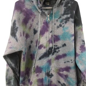 Może przedstawiać: Szara bluza z kapturem zapinana na zamek błyskawiczny z wzorem tie-dye w odcieniach fioletu, niebieskiego, zielonego i czarnego.