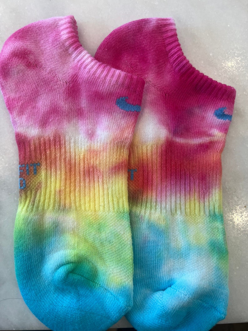 May include: A pair of tie-dye ankle socks in shades of pink, yellow, green, and blue. The socks have a white background with a tie-dye pattern.