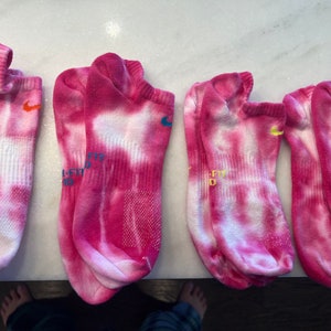 May include: Four pairs of pink and white tie-dye ankle socks with a Nike logo on each sock.