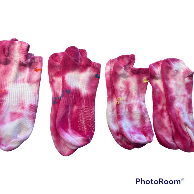 May include: Three pairs of pink and white tie-dye no-show socks with a Nike logo on each sock.