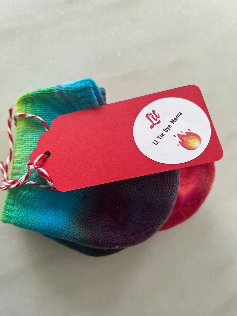 May include: A pair of tie-dye socks with a red tag that says "Lit" and "Li Tie Dye Mama" with a flame icon.