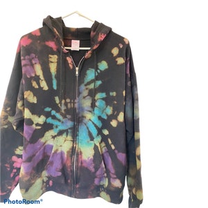 Może przedstawiać: Czarna bluza z kapturem w stylu tie-dye z wirującym wzorem w kolorze fioletowym, niebieskim i zielonym.