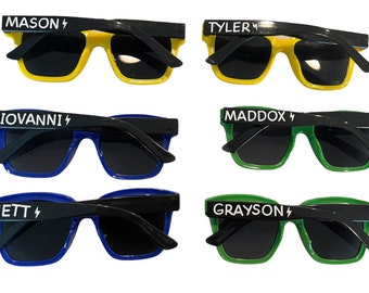 May include: Six pairs of sunglasses with black frames and dark lenses. Each pair has a different coloured frame: yellow, blue, green. Each pair has a name printed in white with a lightning bolt symbol.