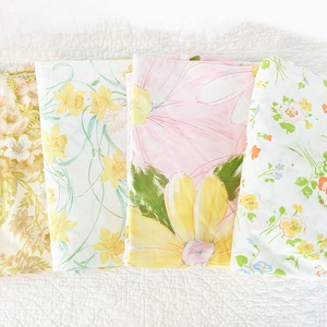 May include: Four different floral patterned fabric swatches. The swatches are arranged horizontally, with the top edge of each swatch aligned. The swatches feature a variety of floral patterns in shades of yellow, pink, and green.