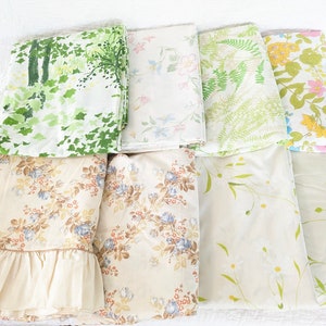 May include: A collection of eight vintage floral patterned bed sheets in various shades of green, white, and brown. The sheets feature different floral designs, including ferns, leaves, and flowers.