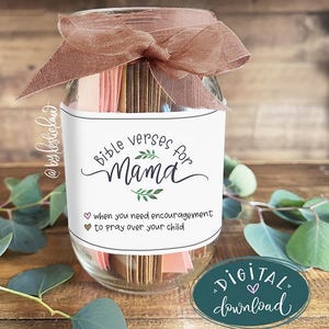 Op de afbeelding: Een glazen pot gevuld met kleine kaarten, vastgebonden met een bruin lint. De pot heeft een wit etiket met de tekst "Bible verses for Mama" en een boodschap over aanmoediging. Een digitale download-afbeelding staat rechtsonder.