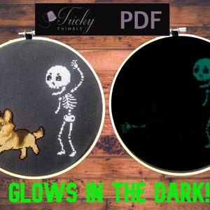 May include: Cross-stitch embroidery in a wooden hoop. One side shows a skeleton and a dog, the other glows in the dark. The text "GLOWS IN THE DARK!" is at the bottom. The top has the text "PDF" and "Tricky Thimble".