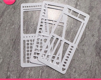 May include: Three silver bullet journal stencils with various cut-out shapes, including rectangles, grids, and decorative elements. The stencils are stacked on a gray surface. The text "bullet journal stencil" is at the bottom.