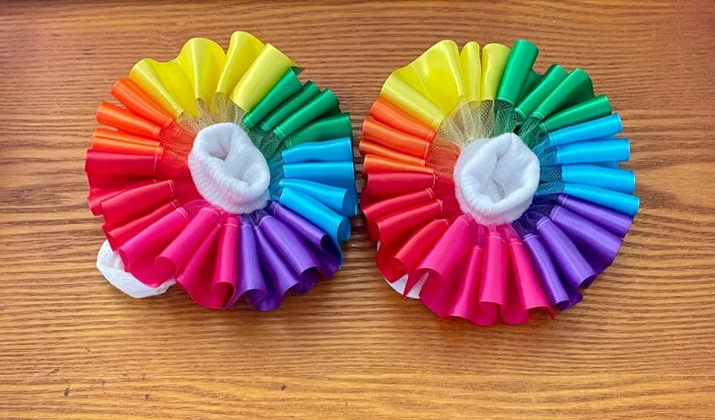 May include: A pair of rainbow-colored baby socks with a white ruffle trim and a white sock liner. The socks are made of a soft, stretchy fabric and are perfect for a baby's delicate feet.