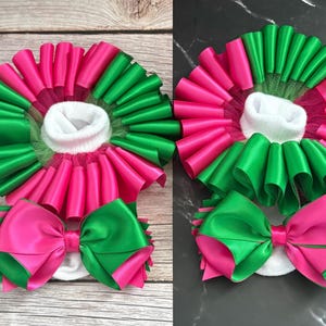 May include: Two pairs of baby socks with green and pink ruffled trim and matching bows. The socks are white with a tulle overlay.