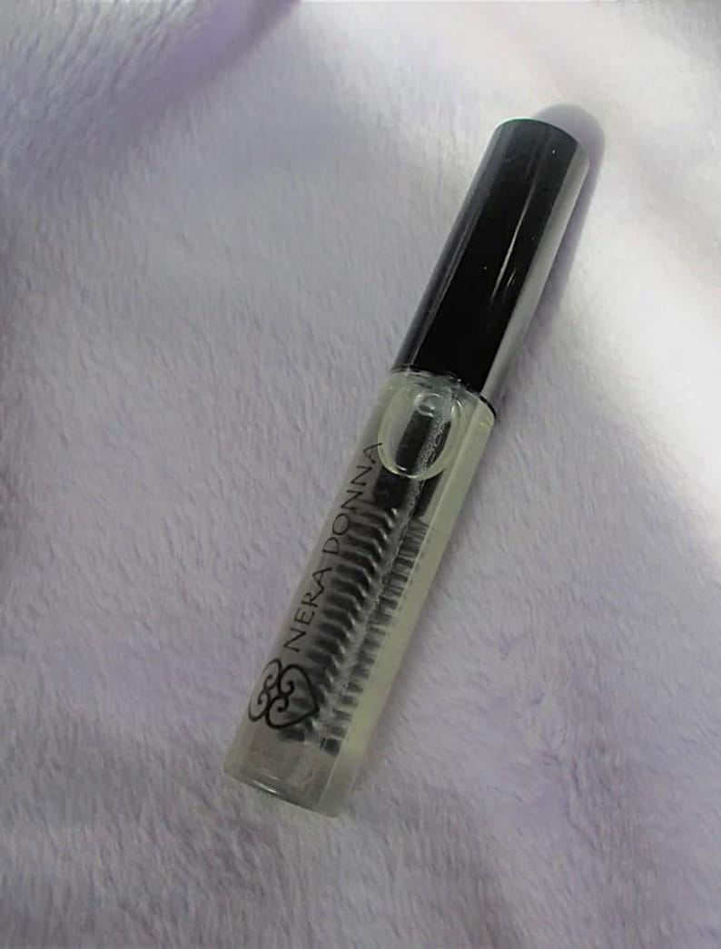 May include: A clear glass bottle with a black cap and a black brush applicator. The bottle is labeled "Nera Donna" with a heart symbol.