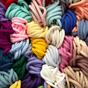 May include: A vibrant assortment of colorful rope bundles. The image showcases a variety of hues, including pink, yellow, blue, green, and purple. The ropes are tightly coiled, creating a textured and visually appealing display. Ideal for crafting or decorative projects.
