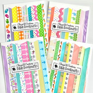May include: Four Bible bookmarks with colorful ribbon designs. Each bookmark features a variety of patterns, including Easter themes with carrots, bunnies, and crosses. The bookmarks have the text "Chrissie B Creations Bible Bookmarks" on a white label.