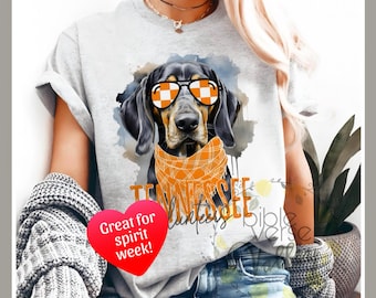 May include: Gray t-shirt with a black and white illustration of a dog wearing orange and white checkered sunglasses and a bandana. The text "Tennessee Volunteers" is printed on the shirt. The text "Great for spirit week!" is printed on a red heart.