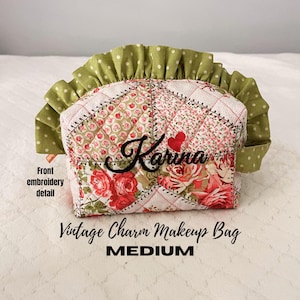May include: A medium-sized vintage charm makeup bag with a patchwork design. The bag features floral patterns in red, pink, and green, with a green polka-dot ruffle. The name "Karina" is embroidered in black, with a red heart. The text "Vintage Charm Makeup Bag" and "MEDIUM" are also visible.