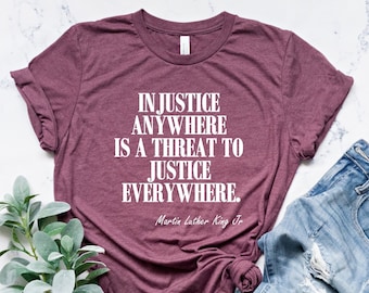 May include: A maroon t-shirt with the quote "Injustice anywhere is a threat to justice everywhere." by Martin Luther King Jr. printed in white.