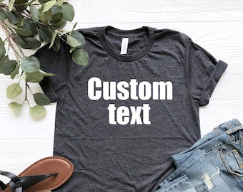 May include: A dark heather grey t-shirt with the text "Custom text" printed in white on the front.