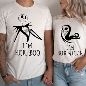 Puede incluir: Dos camisetas blancas con dise&ntilde;os gr&aacute;ficos negros. La primera camiseta presenta una ilustraci&oacute;n en blanco y negro de Jack Skellington de Pesadilla antes de Navidad con el texto "I'm Her Boo". La segunda camiseta presenta una ilustraci&oacute;n en blanco y negro de Sally de Pesadilla antes de Navidad con el texto "I'm His Witch".
