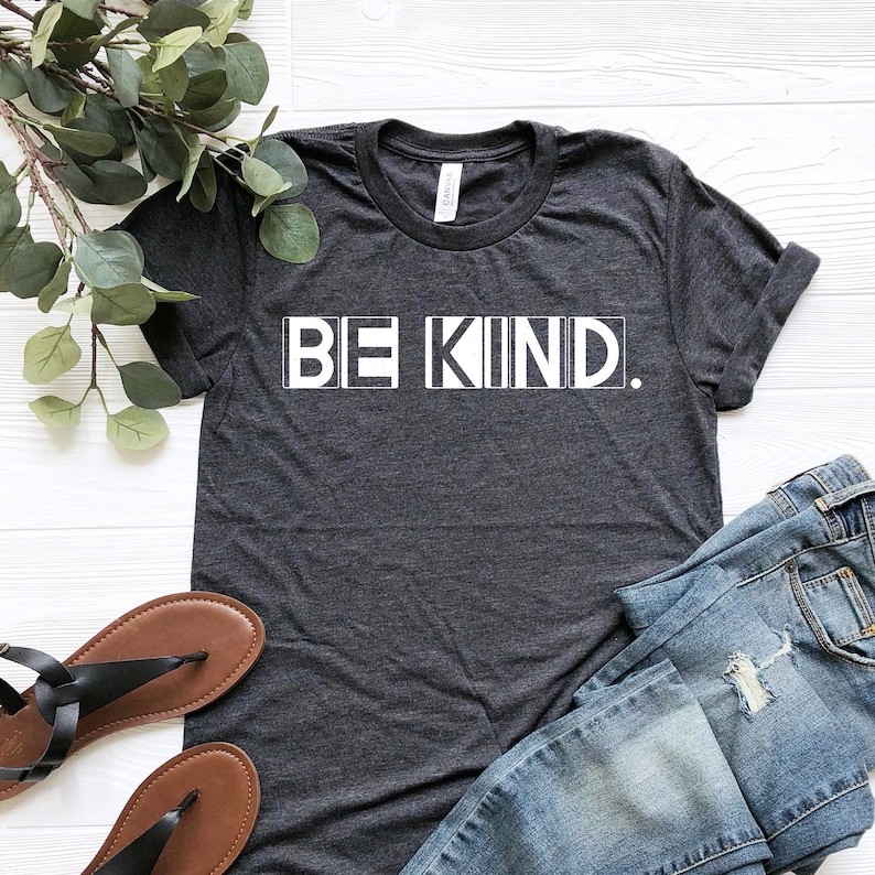 Puede incluir: Una camiseta gris oscuro con las palabras "BE KIND." impresas en blanco en la parte delantera.
