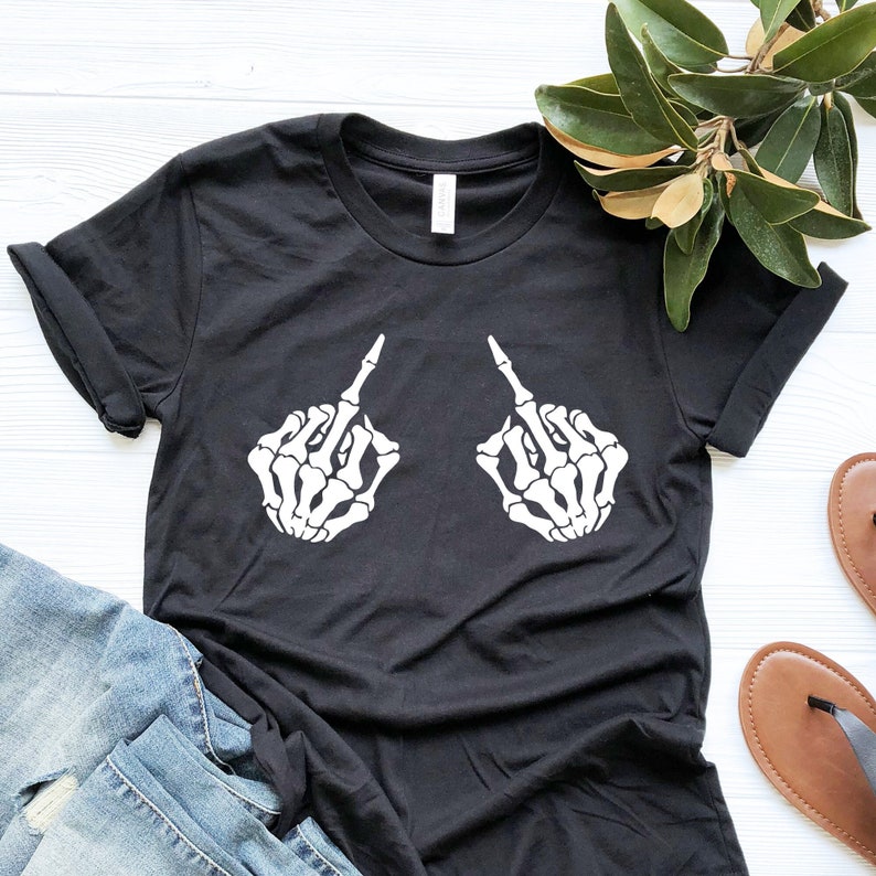 Op de afbeelding: Zwart T-shirt met een witte afbeelding van twee skelethandjes die de middelvinger opsteken.