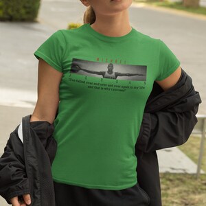 Op de afbeelding: Groen T-shirt met een zwart-witte afbeelding van Michael Jordan met de tekst "MICHAEL JORDAN" en de quote "Ik ben keer op keer gefaald en dat is de reden waarom ik succesvol ben."