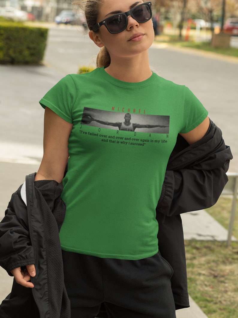 Op de afbeelding: Groen T-shirt met een zwart-witte afbeelding van Michael Jordan met de tekst "MICHAEL JORDAN" en de quote "Ik ben keer op keer gefaald en dat is de reden waarom ik succesvol ben."