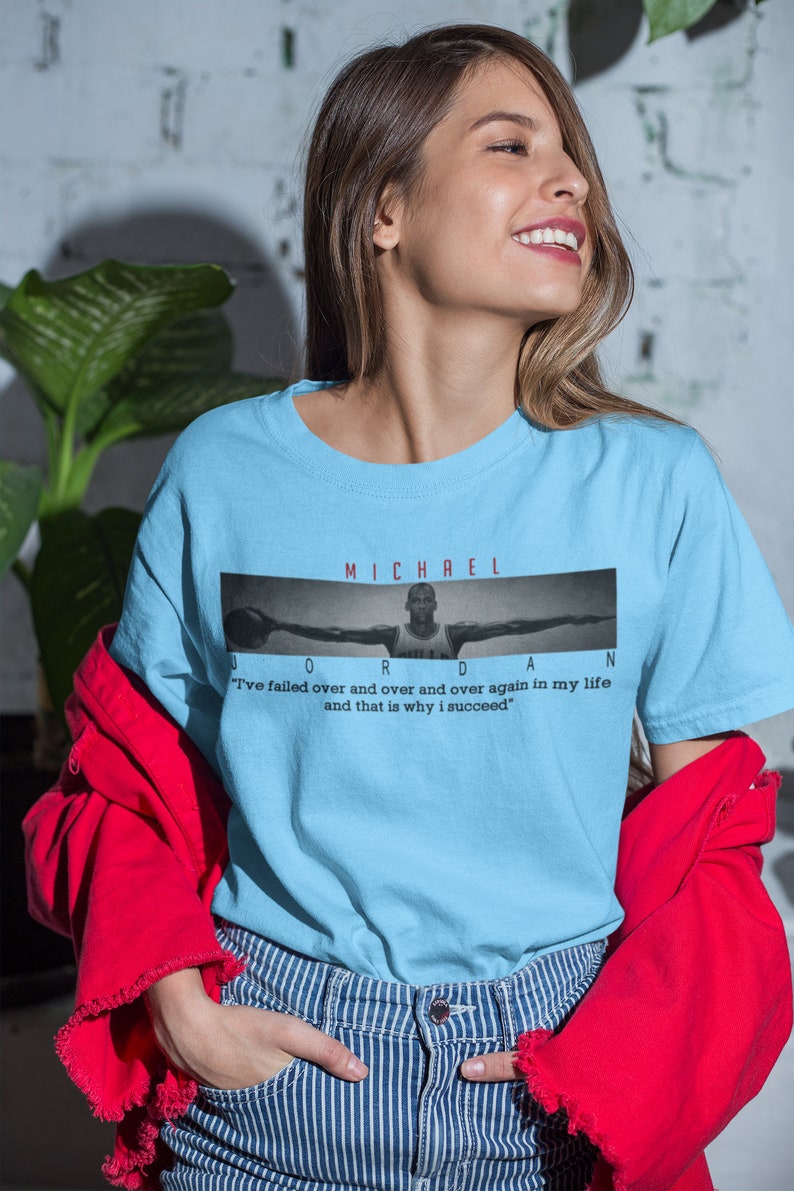 Op de afbeelding: Lichtblauw T-shirt met een zwart-witte afbeelding van Michael Jordan met de tekst "MICHAEL JORDAN" en de quote "Ik ben keer op keer gefaald en dat is waarom ik succesvol ben."