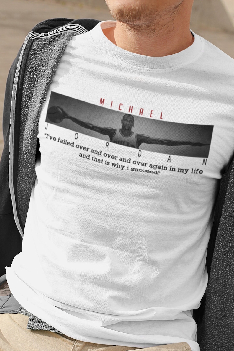 Op de afbeelding: Wit T-shirt met een zwart-witte afbeelding van Michael Jordan met de tekst "MICHAEL JORDAN" boven de afbeelding en de quote "Ik ben keer op keer gefaald en dat is waarom ik succesvol ben." onder de afbeelding.