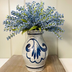 May include: A blue and white ceramic vase with a floral design, filled with a bouquet of light blue flowers.