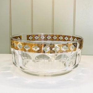 May include: A clear glass bowl with a gold and white geometric pattern around the rim. The bowl has a fluted design.