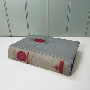 Puede incluir: Un libro de tapa dura gris con letras doradas en el lomo y un título rojo en la portada. El título es "SELECTED POEMS BY ROBERT FROST".