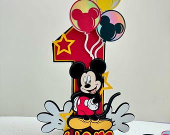 May include: A red and yellow number one cake topper with a Mickey Mouse character, balloons, and the name Liam.