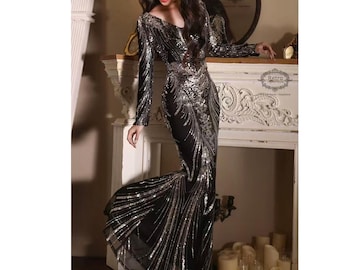 Puede incluir: Un vestido de noche negro de manga larga, adornado con lentejuelas plateadas. El vestido presenta un escote en V y una silueta de sirena, con una falda fluida. El diseño incluye intrincados patrones de lentejuelas.