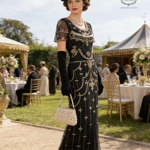 May include: A black vintage-style dress with gold embellishments, a matching hat with a feather, and a pearl-beaded handbag. The dress features a detailed pattern and is worn with long black gloves and high heels. The scene is set at an outdoor event.