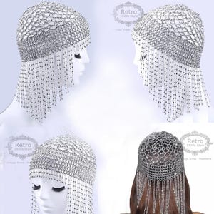 May include: A silver beaded flapper headband with a net design and fringe. The headband is shown on a mannequin head from multiple angles.