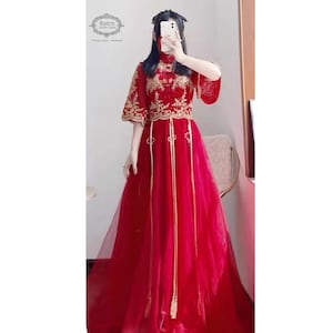 May include: A red and gold Chinese-style dress with a high collar and long sleeves. The dress is made of a sheer fabric with gold embroidery and has a long, flowing skirt.