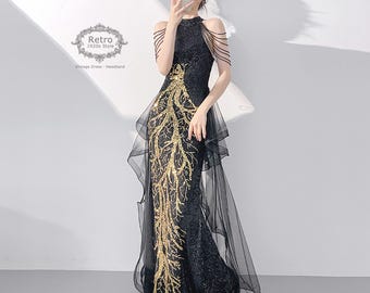 May include: A black and gold sequined gown with a high neckline and a flowing tulle skirt. The gown features a gold sequined design that resembles branches.