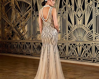 Könnte beinhalten: Silbernes, paillettenbesetztes ärmelloses Kleid mit Meerjungfrau-Silhouette. Das Kleid hat einen tiefen Rücken und einen durchsichtigen, fließenden Rock. Eine Perlenkette und ein Stirnband vervollständigen den Look. Der Hintergrund ist ein gold-schwarzes Art-Déco-Design.