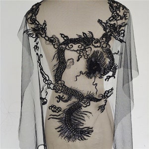 May include: Black beaded dragon applique on a sheer black mesh fabric. The dragon is detailed with intricate beadwork and is a popular embellishment for clothing and accessories.
