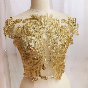 May include: Gold sequined lace applique with a floral design. The applique is on a sheer mesh fabric.