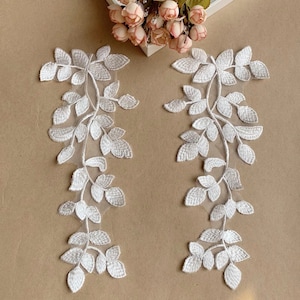 Puede incluir: Dos apliques de encaje blanco con un diseño de hojas. Los apliques son perfectos para agregar un toque de elegancia a cualquier proyecto.