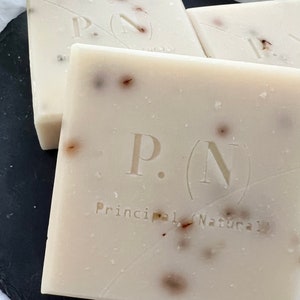 Könnte beinhalten: Drei weiße Seifenstücke mit braunen Flecken. Die Seife ist mit "P. (N) Principal Natural" gekennzeichnet.