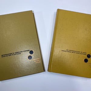 May include: Two yellow hardcover books with black and gold text on the spines. The book on the left has the title "Introduction to Computer Systems Using the PDP-11 and Pascal" and the book on the right has the title "An Introduction to Data Structures with Applications". Both books have a black and gold logo on the bottom right corner.