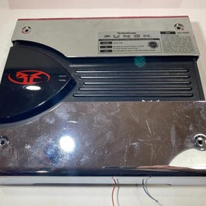 Könnte beinhalten: Ein rechteckiger Rockford Fosgate Punch Auto-Audio-Verstärker mit polierter Chromoberfläche an den oberen und unteren Paneelen, einem schwarzen Mittelteil mit horizontalen Kühlrippen und einem schwarzen runden Logo mit rotem Design.