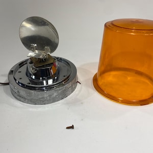 May include: A chrome-plated rotating beacon light with a clear orange dome. The light has a silver reflector and a small screw.