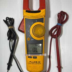 Pu&ograve; includere: Una pinza amperometrica Fluke 336 True RMS gialla e rossa con un display digitale che mostra OL. Il dispositivo &egrave; dotato di una manopola rotante, una ganascia rossa e due puntali collegati, uno con sonda nera e uno con sonda rossa.