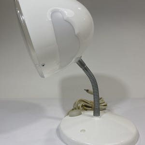 May include: A white ceramic mug with a black handle and the text "But First, Coffee" in a bold, black font. The mug is set against a blurred background, suggesting a cozy setting.