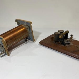 Peut inclure: Une bobine en cuivre vintage avec une base en bois et une clé télégraphique en laiton sur une base en bois.