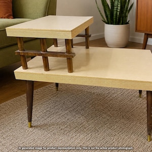 May include: A two-tier step table featuring light cream-coloured rectangular surfaces and dark brown wooden legs. The upper tier is supported by a dark brown wooden frame with vertical slats, while the lower tier rests on four tapered legs.