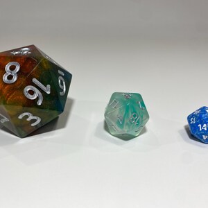 May include: Three different dice, one large and multi-colored, one medium and green, and one small and blue.